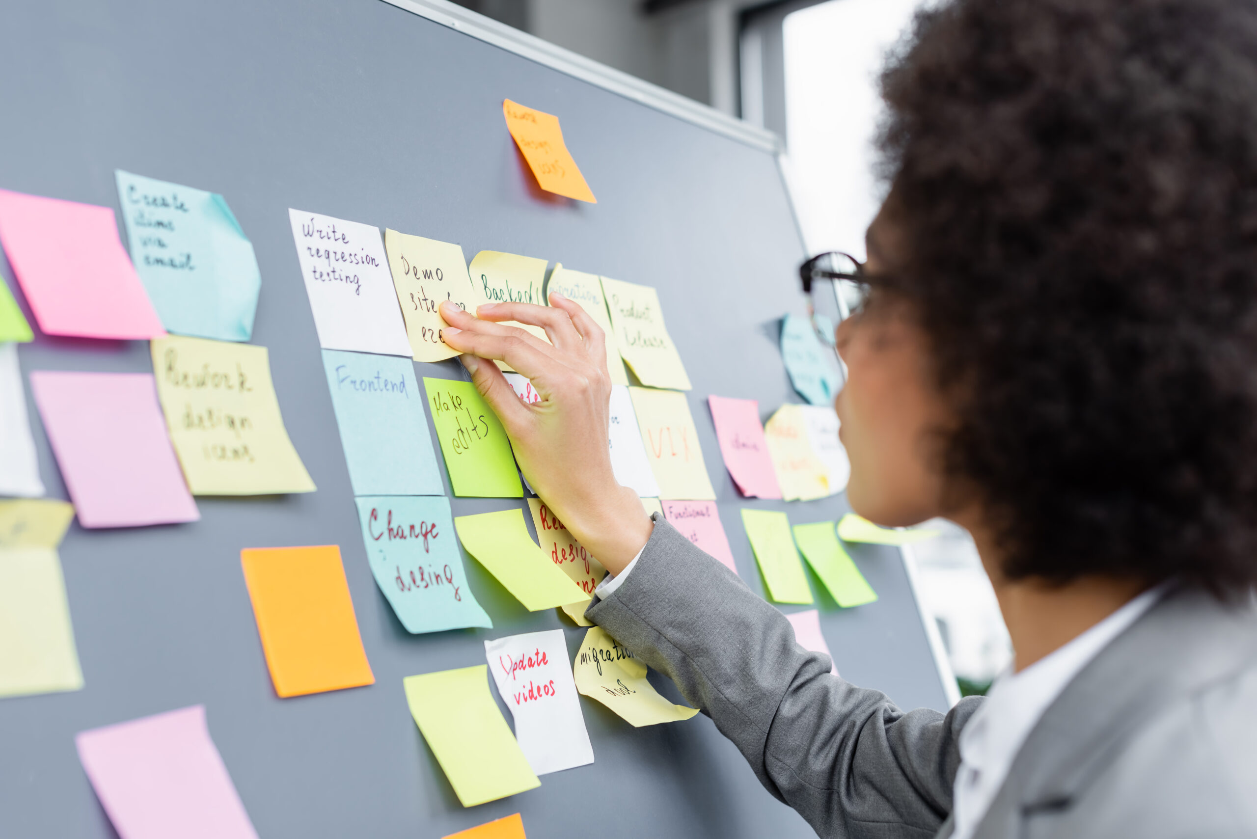 black woman putting stick notes on a blackboard