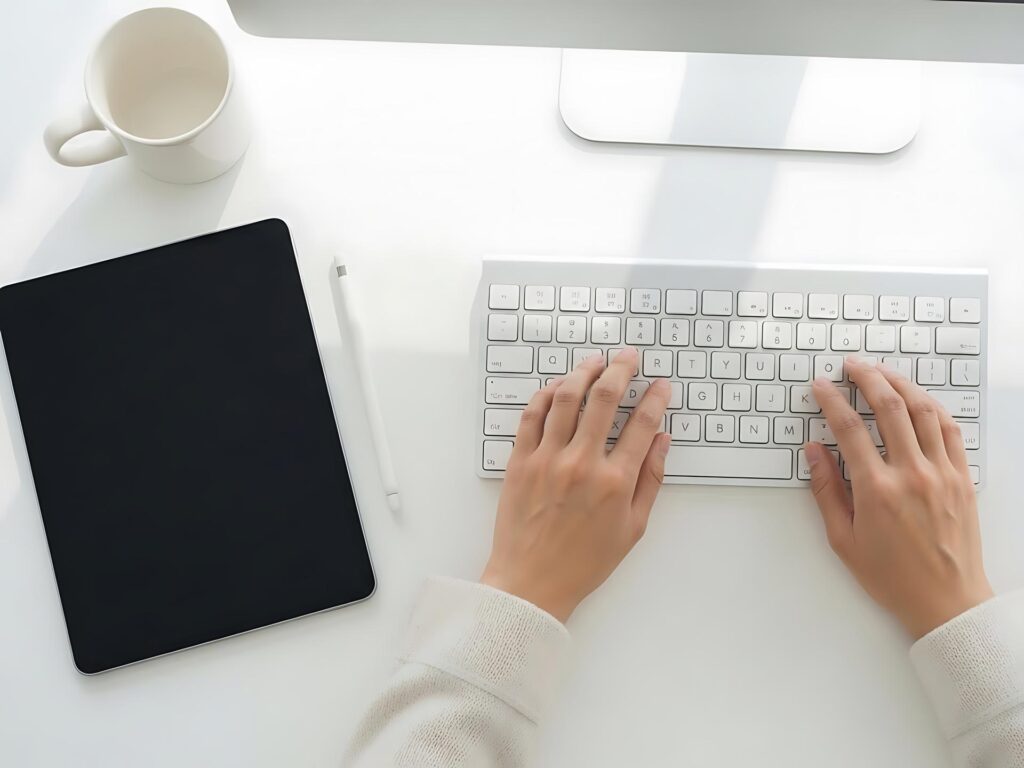 A person typing on a keyboard and using a tablet